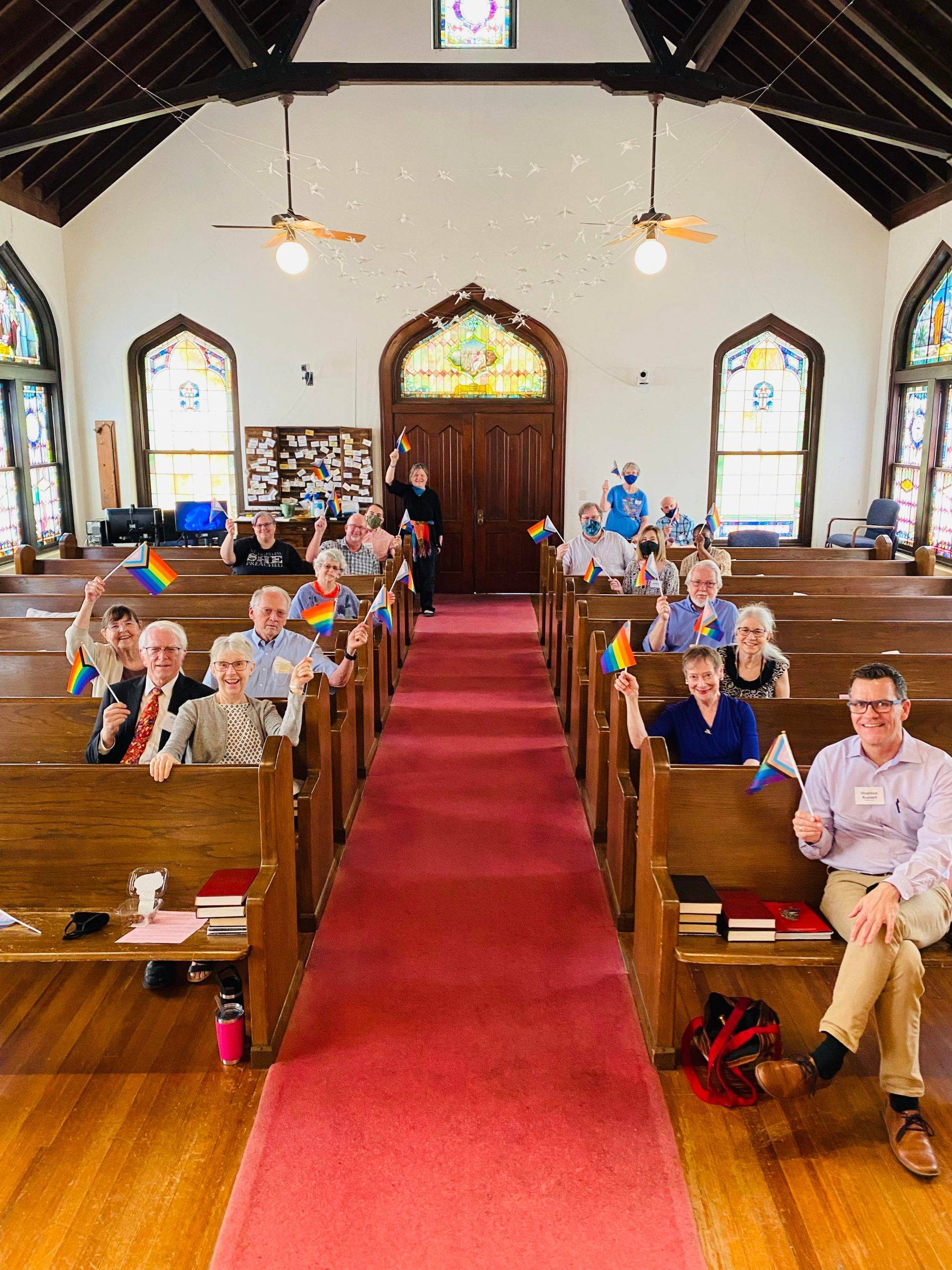 Members of CCA wave progress pride flags from their seats in the sanctuary. 
